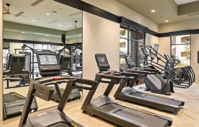 A gym with treadmills, elliptical machines, and other exercise equipment.