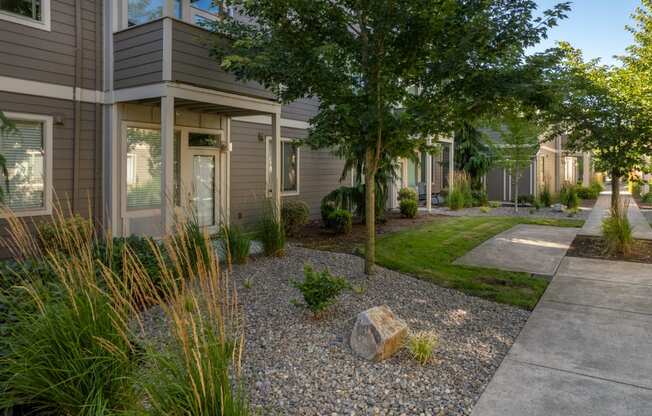a front yard with a tree and a rock in front of a house