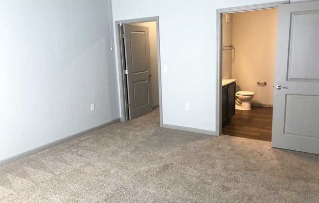 Empty bedroom with a bathroom in the background at Mosaic Apartments in Avon, Indiana