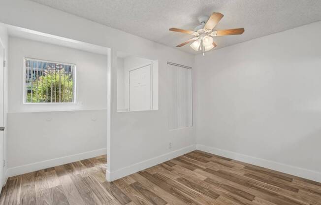 A room with a ceiling fan and wooden flooring.