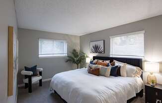 A bedroom with a large bed and a chair.