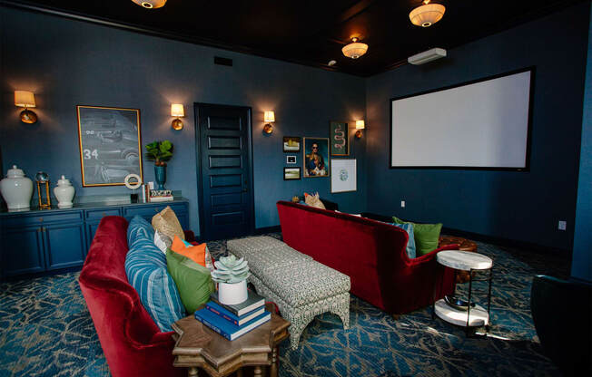 a blue living room with red couches and a projector screen
