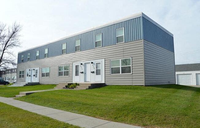 West Fargo, ND Sheyenne Terrace. A gray building with white doors and a green lawn