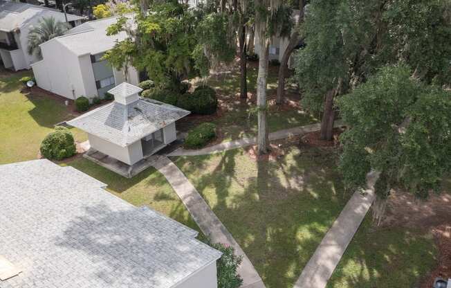 A white house with a grey roof and a small tower-like structure in the front yard.