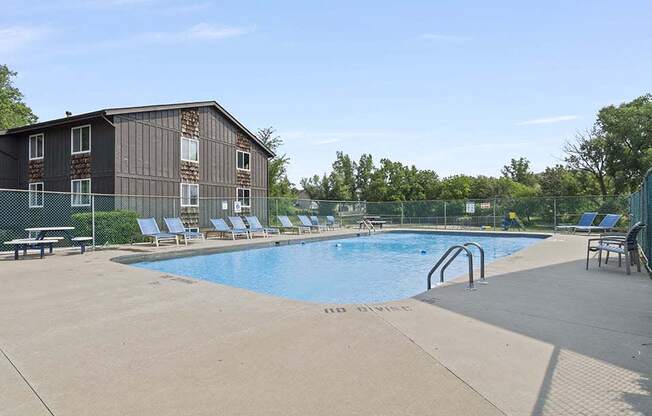 a swimming pool with chaise lounge chairs and a building in the background