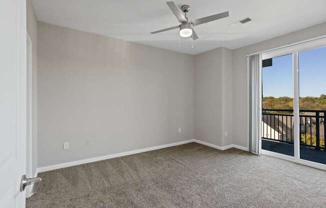 Flatiron West Trade Apartments gray carpeted bedroom with attached balcony