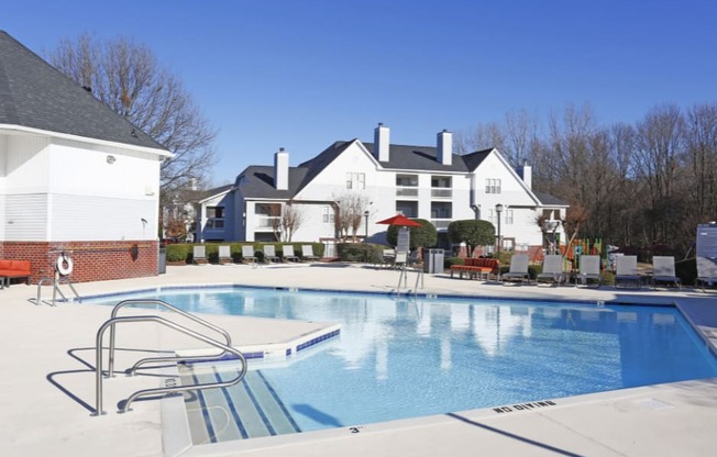 a large pool with chairs around it in front of a house