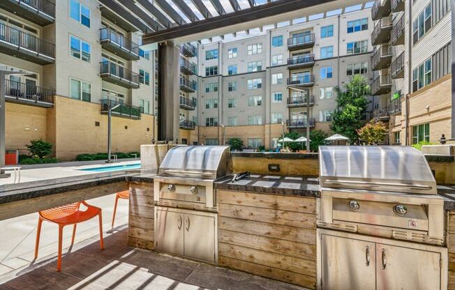 an outdoor kitchen with a grill and a pool in an apartment building at Link Apartments Innovation Quarter, Winston Salem, NC