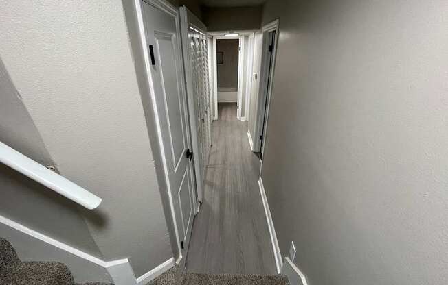 A staircase with a grey carpeted runner and white walls.