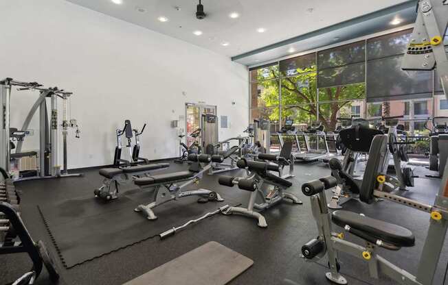 A gym with a variety of equipment including weights and machines at The Kitt at Warner Center Apartments, Woodland Hills, California
