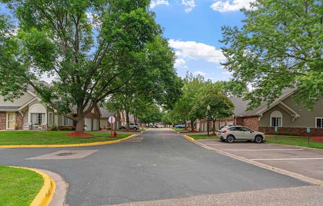 A residential street with houses on both sides and a car parked on the right side.