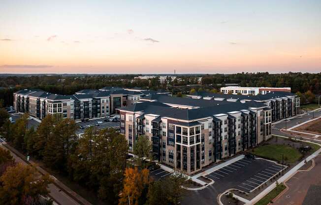 A large, modern building complex with a parking lot in front.