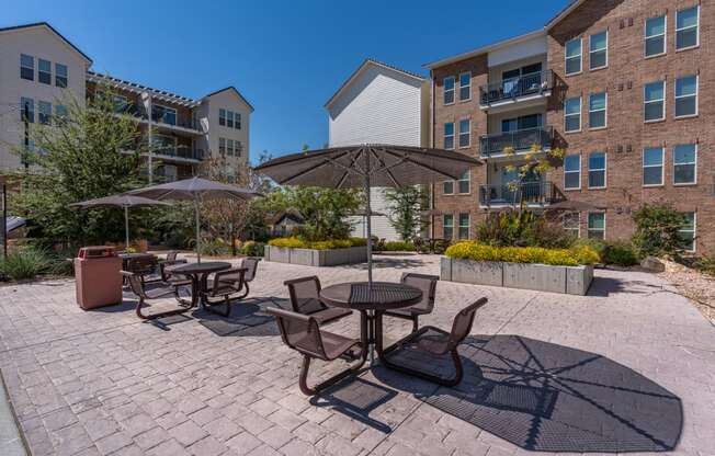 a patio with tables and umbrellas in front of an apartment building