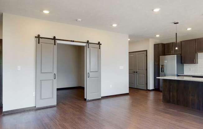 Living space with sliding barn doors leading to an office space in the Melody floor plan at Haven at Uptown in Lincoln, NE