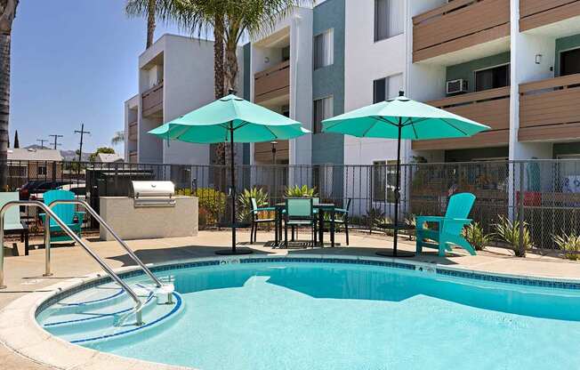 A pool with a slide and chairs with umbrellas.