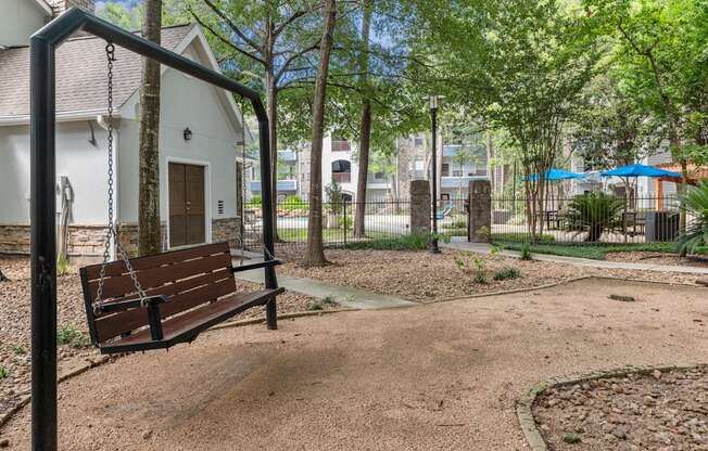 A swing set in a playground with a white building in the background.