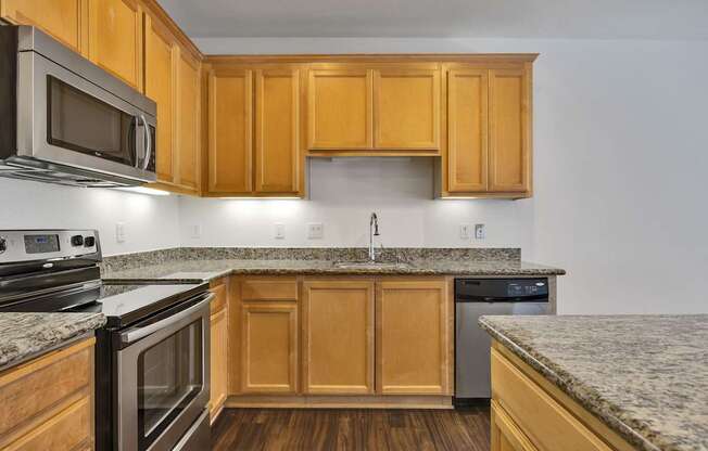an empty kitchen with granite counter tops and wooden cabinets