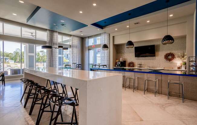 A bar area with a white counter and black chairs.