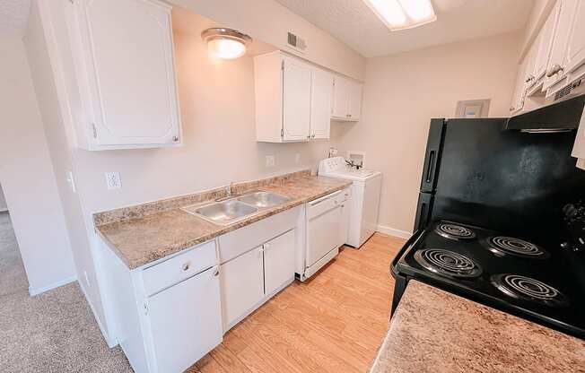 a kitchen with white cabinets and a black stove and a sink