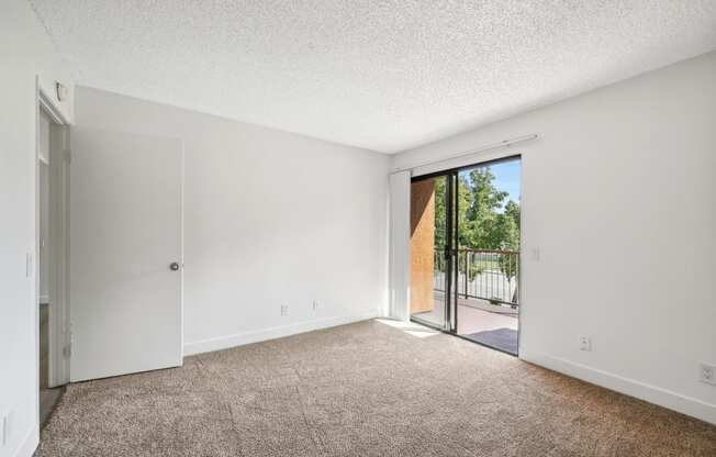 an empty living room with a sliding glass door to a patio