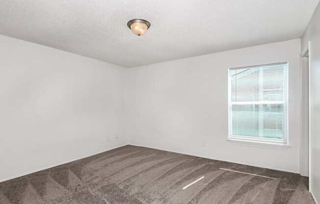 an empty room with a window and a rug on the floor