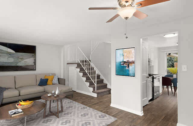 A living room with a brown ceiling fan and a grey rug.