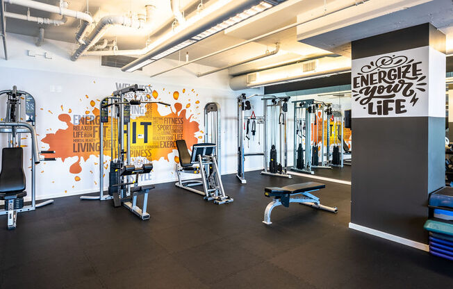 a workout room with weights and other exercise equipment and a wall with a mural