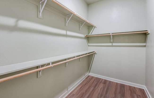 A white wall with a shelf and a brown floor.