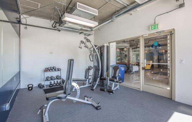A gym with a variety of equipment including a squat rack, dumbbells, and a bench press.
