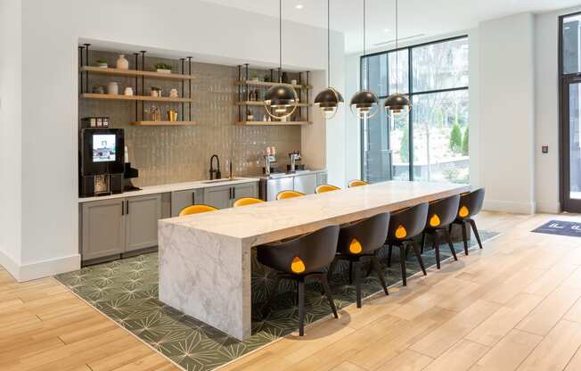 a kitchen with a marble counter top and a long table with yellow chairs