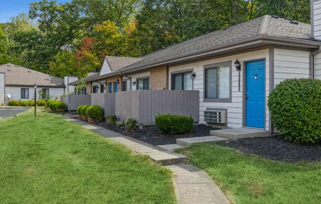 a sidewalk in front of a house with a blue door