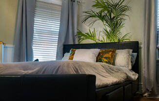 Brookmore one bedroom apartment in Pasadena CA with luxury bedding, a dark leather headboard, and six visible pillows on a bed situated diagonally