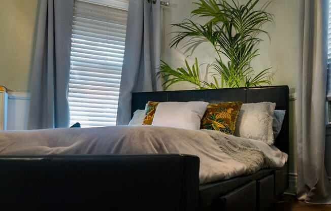 Brookmore one bedroom apartment in Pasadena CA with luxury bedding, a dark leather headboard, and six visible pillows on a bed situated diagonally