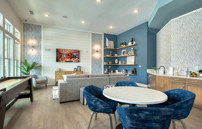 A modern living room with a dining table and blue chairs.
