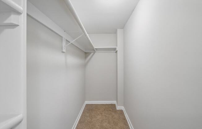 a spacious closet in a home with white walls and carpet