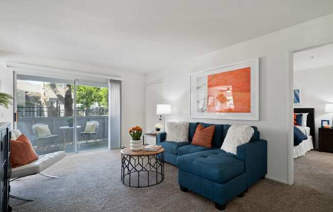 a living room with a blue couch and a coffee table and a sliding glass door