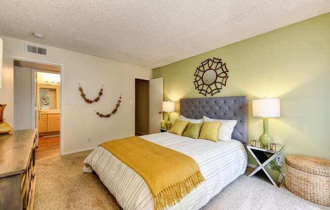 Bedroom with Carpet, light green accent Wall, two nightstands and yellow throw blanket on the bed.