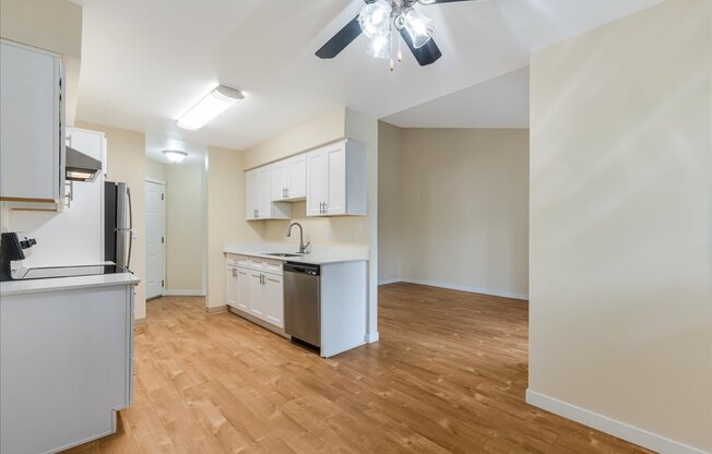 A kitchen with white cabinets and a wooden floor.