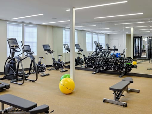 a gym with cardio machines and weights and a yellow ball on the floor at The Encore at Ingram Manor, Pikesville, 21208