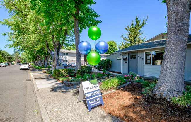 a sidewalk with a sign and balloons in front of a building