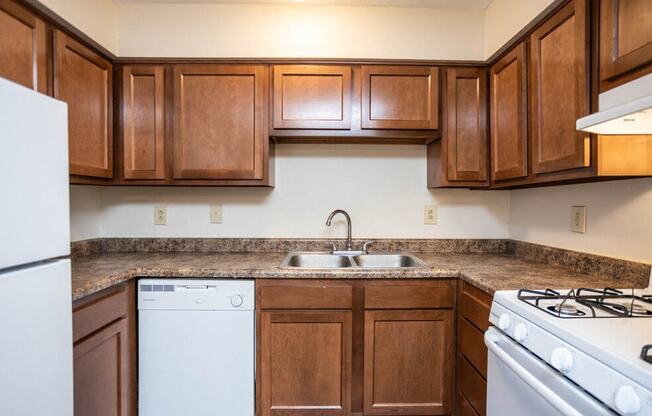 a kitchen with wood cabinets and white appliances and a sink