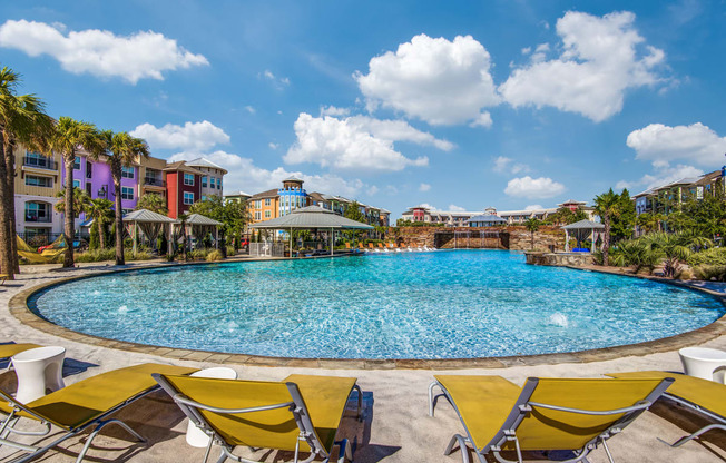 Apartments in Lewisville TX- Exterior Image of Hebron 121 Station's Expansive Pool with Yellow Chaise Chairs, Cabanas, and Gazebo
