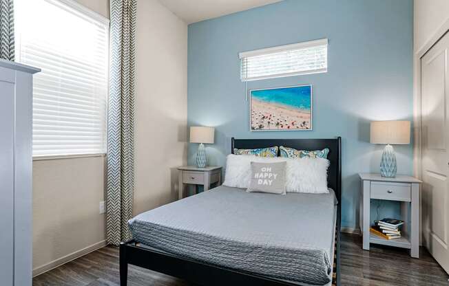 a bedroom with a bed and two nightstands and a window