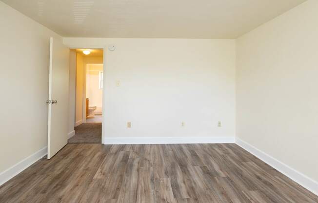 a bedroom with hardwood floors and white walls