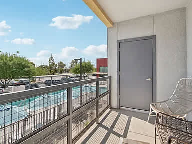 A balcony with a chair and a pool in the background.