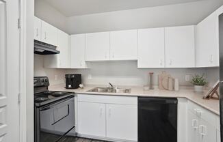 an empty kitchen with white cabinets and black appliances