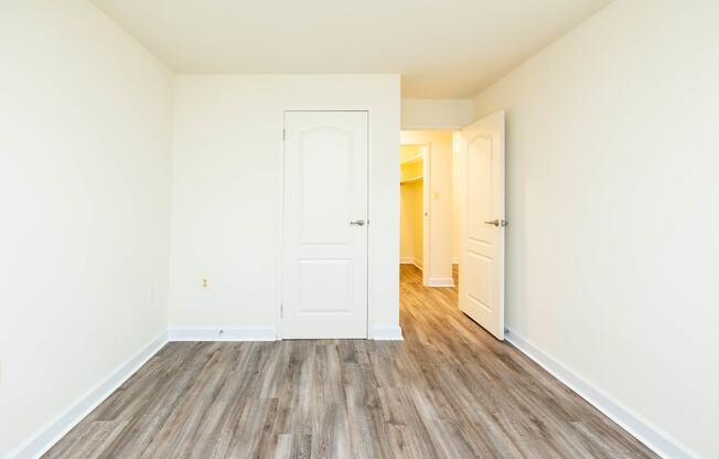 a bedroom with hardwood floors and white walls