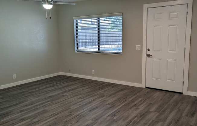 an empty living room with wooden floors and a white door