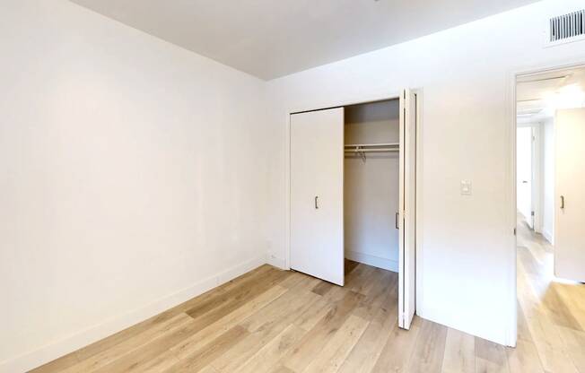 A room with a white wall and a wooden floor with a white door.