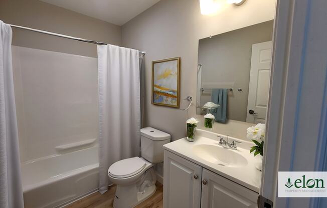 A white bathroom with a toilet, sink, and shower.